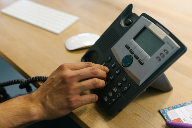 Business Telephone - Person Dialing the Telephone